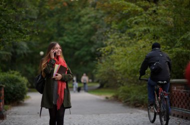 Sonbahar parkta genç çekici kadın yürüyor.