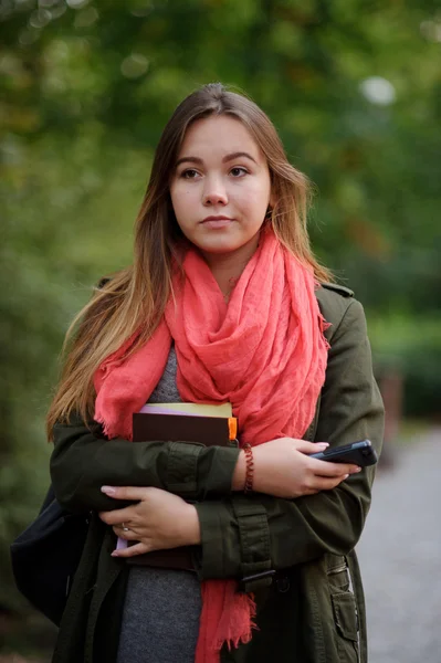 Girl in easy coat and bright red scarf thoughtfully looks into the camera. — Stock Photo, Image