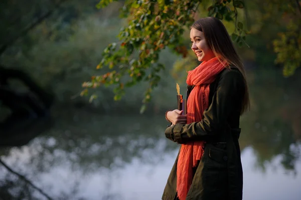 Lovely girl in a bright red scarf walks in autumn park. — Stock Photo, Image