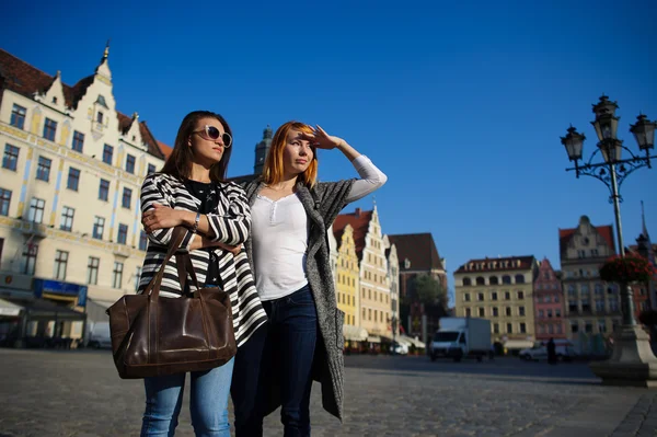 Två attraktiva flickvänner stå i kullerstensbelagda torget i vackra stad — Stockfoto