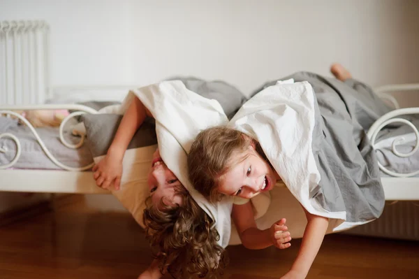 Crianças, menino e menina se entregam na cama no quarto . — Fotografia de Stock