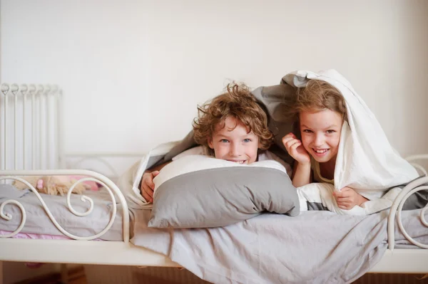 Kleine broer en zus maakte een play op het bed in de slaapkamer. — Stockfoto