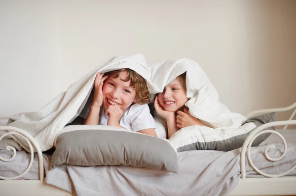 Twee kinderen, broer en zus, squirmy op het bed in de slaapkamer. — Stockfoto