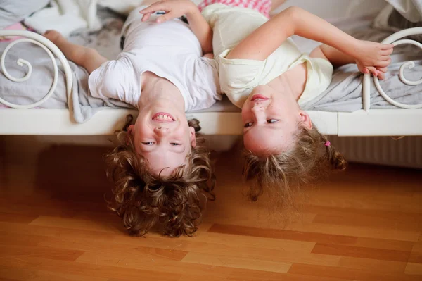 De kinderen, een jongen en een meisje, ondeugende op het bed in de slaapkamer. — Stockfoto