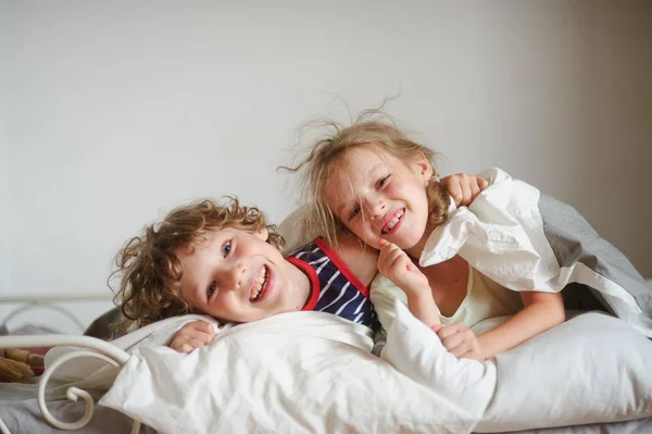 Due bambini, fratello e sorella, si divertono su un letto in camera da letto . — Foto Stock