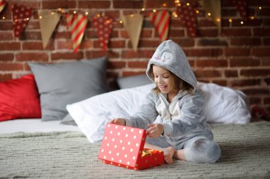 Noel tatili. Sevimli kız 8-9 yıl, onun elinde bir kutu ile yatakta oturur.