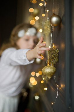 8-9 yıl zevk ile Beyaz giysili kız altın Noel çelenk dokunur.