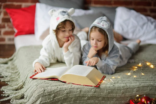 Weihnachtsferien. Bruder und Schwester lagen im weichen Schlafanzug auf einem Bett. — Stockfoto