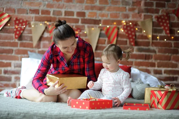 Молодая женщина с маленькой дочерью упаковать рождественские подарки . — стоковое фото
