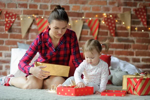 Mladá žena s malou dcerou zabalit vánoční dárky. — Stock fotografie