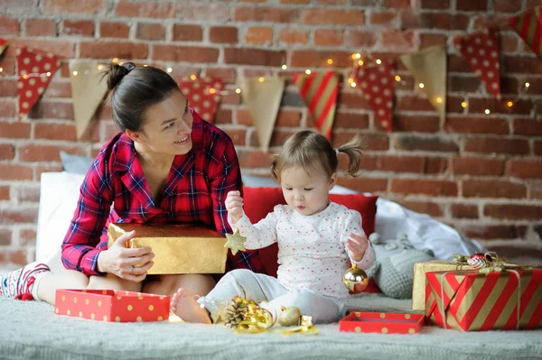 Junge Frau mit kleiner Tochter packt Weihnachtsgeschenke ein. — Stockfoto