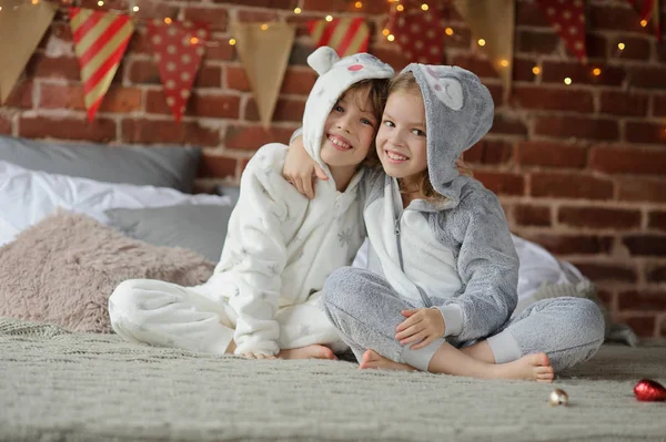Két gyermek ült az ágy várja karácsonyi ajándékokat pizsamában. — Stock Fotó