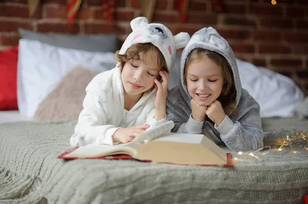 Zwei Kinder liegen auf großem Bett und lesen Märchen. — Stockfoto