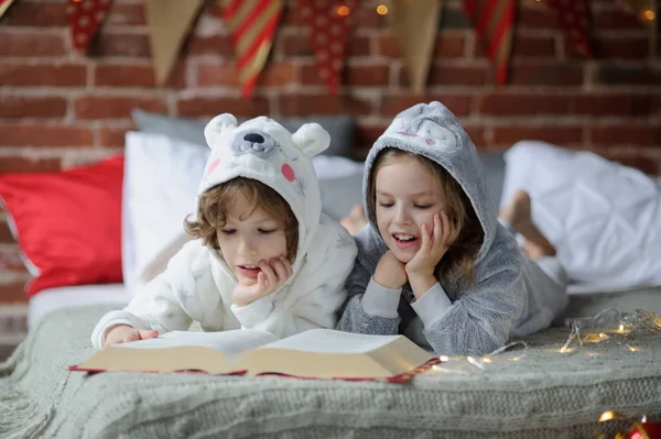 Los niños leen un gran libro con cuentos de Navidad . — Foto de Stock