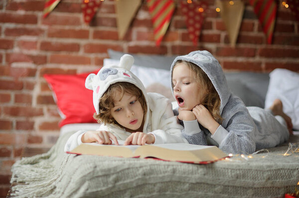 Двое детей, брат и сестра, читают рождественские сказки
.