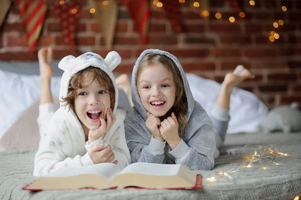 Dua anak, kakak dan adik, membaca cerita Natal . — Stok Foto