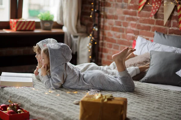 Los niños leen un gran libro con cuentos de Navidad . — Foto de Stock