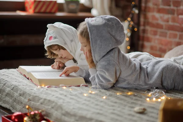 Los niños leen un gran libro con cuentos de Navidad . —  Fotos de Stock