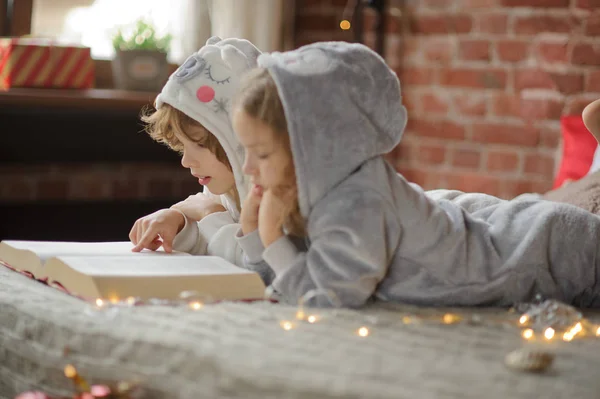 Dos niños, hermano y hermana, leen cuentos de Navidad . — Foto de Stock