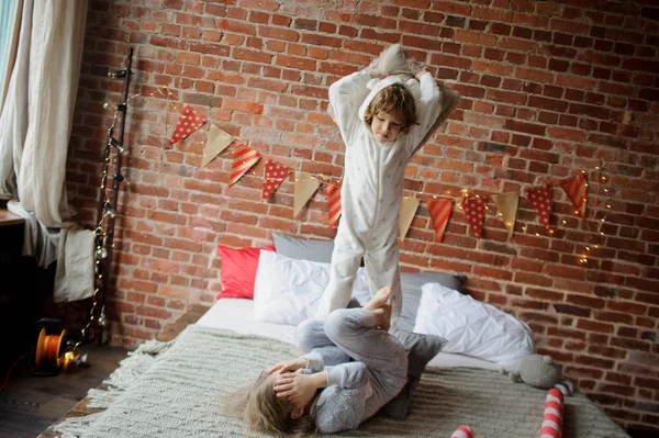 Two children in soft pyjamas have arranged fight by pillows. — Stock Photo, Image
