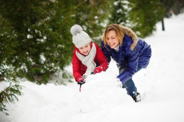 Anne ile kızı bir kardan adam park inşa.