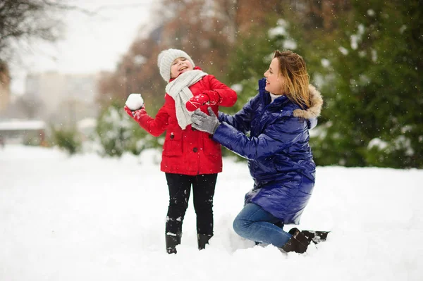 Mother and daughter cheerfully spend time in winter day.