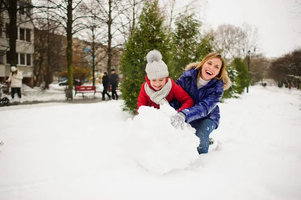 젊은 학교 나이의 딸으로 어머니는 마당에 눈사람을 구축. — 스톡 사진
