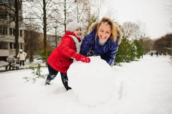 젊은 학교 나이의 딸으로 어머니는 마당에 눈사람을 구축. — 스톡 사진