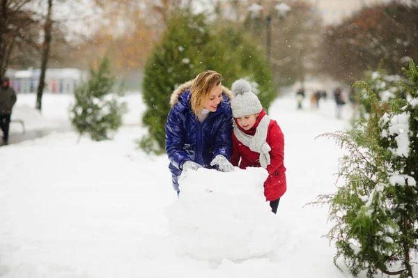 어머니 젊은 학교 나이의 딸과 함께 공원에서 눈사람을 구축. — 스톡 사진