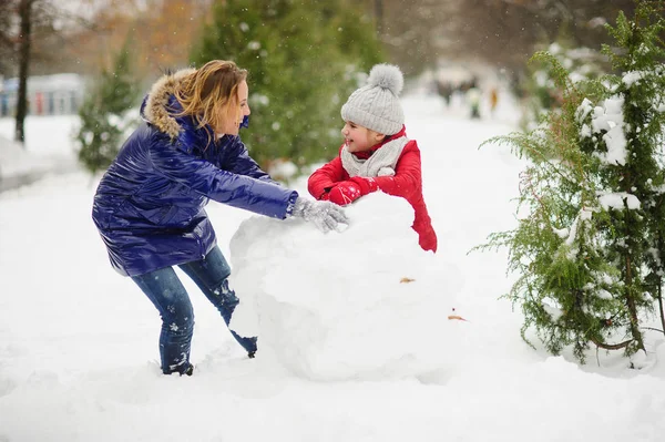 어머니 젊은 학교 나이의 딸과 함께 공원에서 눈사람을 구축. — 스톡 사진