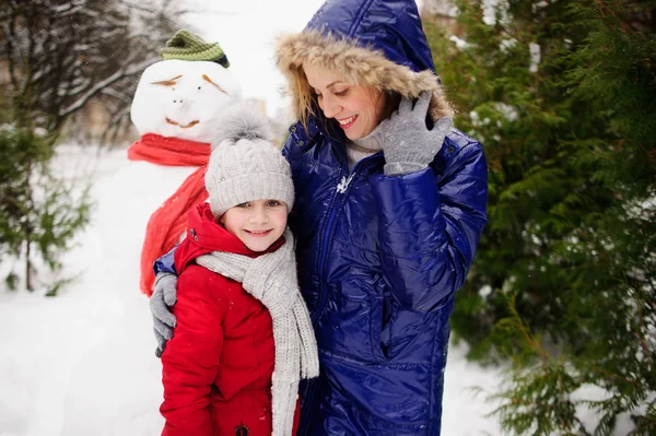 Mère avec fille ont construit un bonhomme de neige et se réjouissent . — Photo