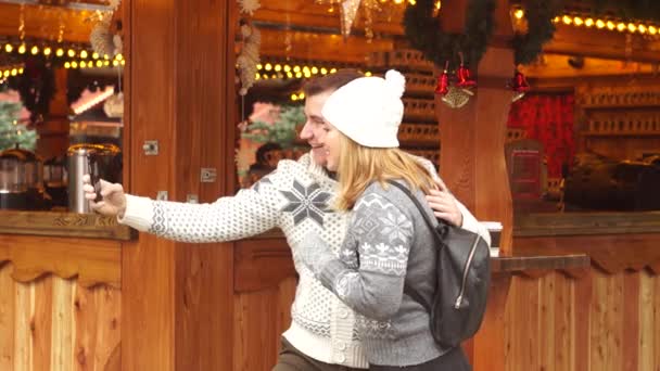 Um homem segura um telefone inteligente na mão e faz uma selfie. Feliz Natal! . — Vídeo de Stock