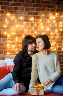 Boxing Günü. Büyük bir yatağa yuvalanmış genç çift oturur.