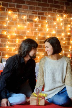 Boxing Günü. Büyük bir yatağa yuvalanmış genç çift oturur.