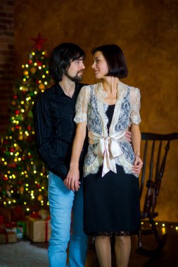 Güzel genç çift Noel ağacının yanında duruyor.