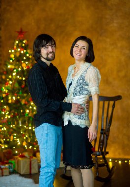 Güzel genç çift Noel ağacının yanında duruyor.