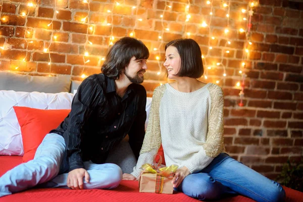 Tweede kerstdag. Het jonge paar zit hebben genesteld op een groot bed. — Stockfoto