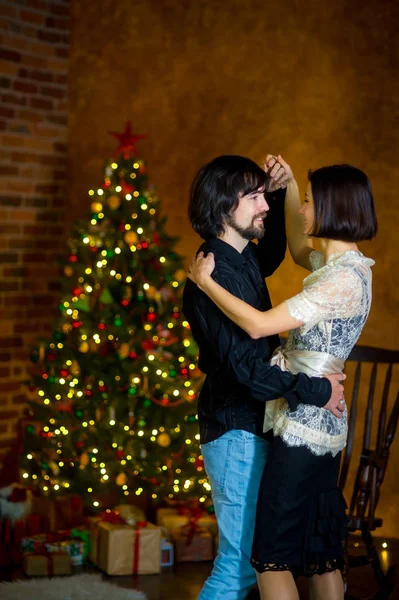 La hermosa pareja joven baila cerca del árbol de Navidad . — Foto de Stock