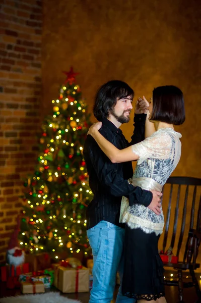 The beautiful young couple dances near the Christmas tree. — Stock Photo, Image