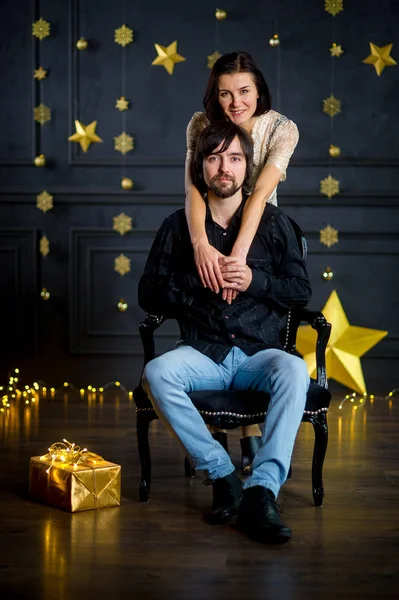 Young woman embraces man sitting in a chair. — Stock Photo, Image
