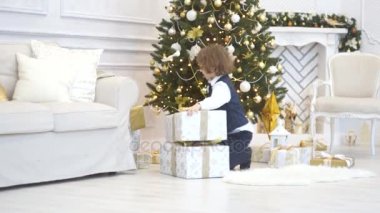 Genç okul çağındaki çocuk tüm hediyeler Noel ağacının altında toplar. 
