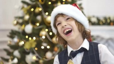 Yakışıklı genç okul çağındaki Noel ağacının yanında güler.