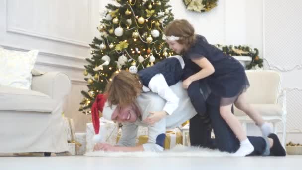 Der Vater spielt mit Kindern am Weihnachtsbaum. — Stockvideo