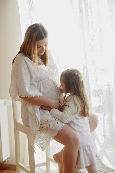 Charming little girl hugging her pregnant mother. — Stock Photo, Image