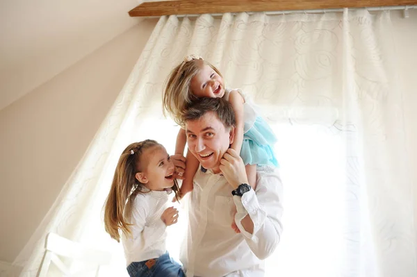 Young man cheerfully spends time with the little daughters. — Stock Photo, Image