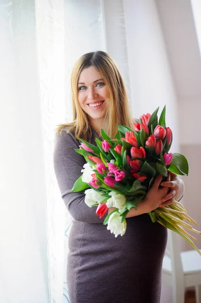 Красивая беременная женщина с огромным букетом разноцветных тюльпанов . — стоковое фото