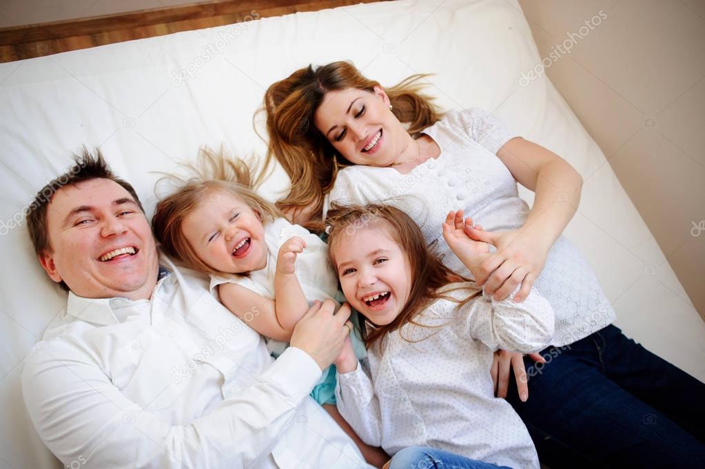 Big closeknit family from four people cheerfully spends time for beds