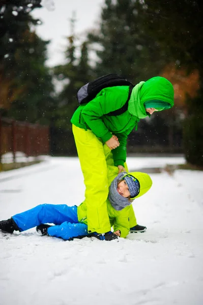 Zwei Jungen in hellen WinterOveralls spielen auf Schnee. — Stockfoto