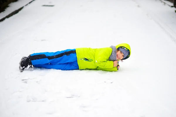 The cheerful boy of school age lies on snow. — Stock Photo, Image