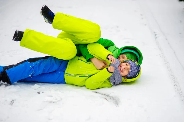 Zwei Jungen in hellen WinterOveralls spielen auf Schnee. — Stockfoto